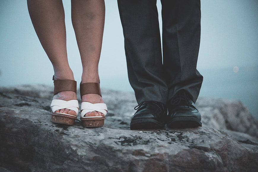 Couple's Feet Standing on Rocky Cliff Edge