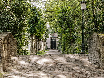 Cobblestone path leading to historic building in Bruges park
