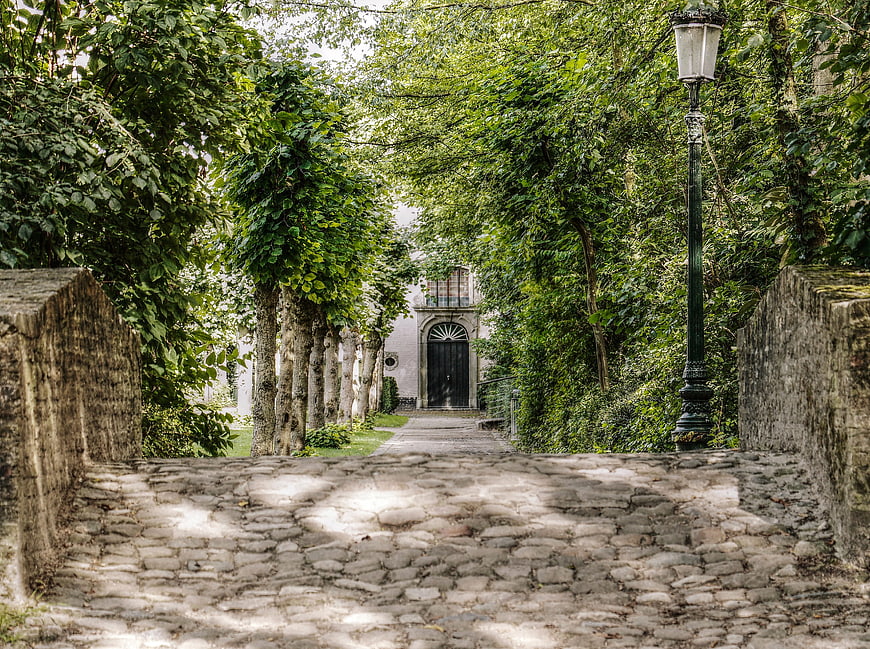 Cobblestone path leading to historic building in Bruges park