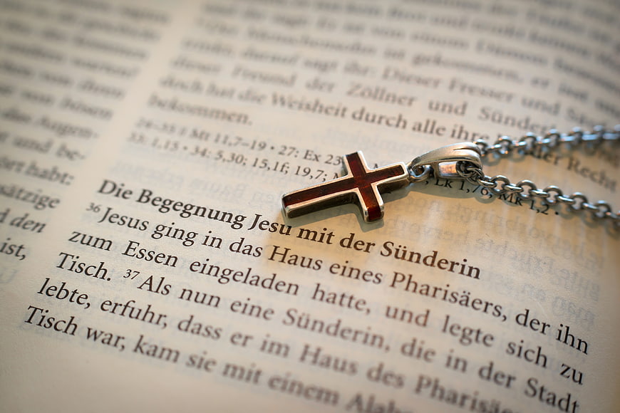 Silver Cross Necklace on German Bible Page