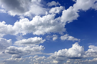 Fluffy white cumulus clouds against a vibrant blue sky