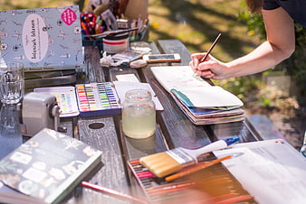 Woman painting watercolors outdoors on a wooden table