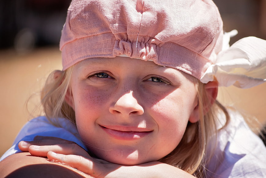 Close-up portrait of smiling young girl in pink hat
