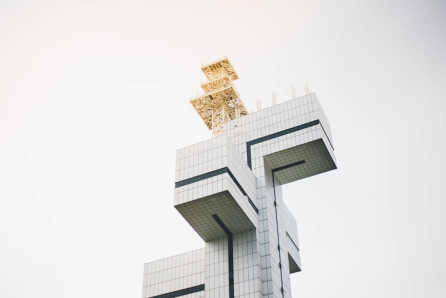 Modern geometric architecture with yellow lattice tower against white sky