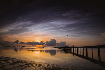 Dramatic Sunset Over Wooden Pier and Calm Water