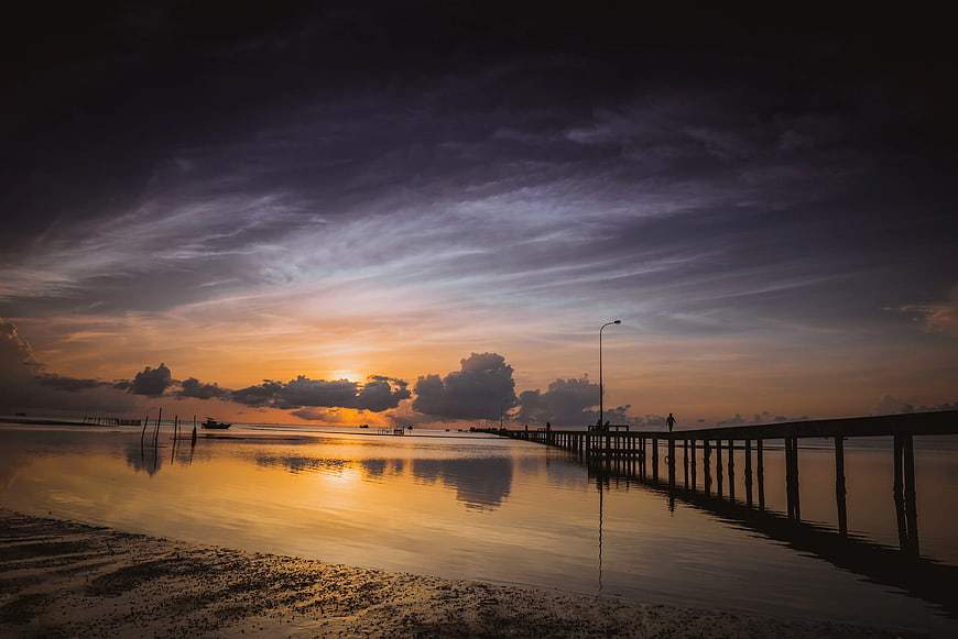 Dramatic Sunset Over Wooden Pier and Calm Water