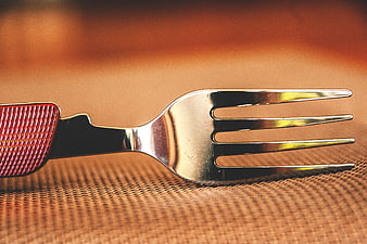Close-up of silver fork with red handle on textured surface