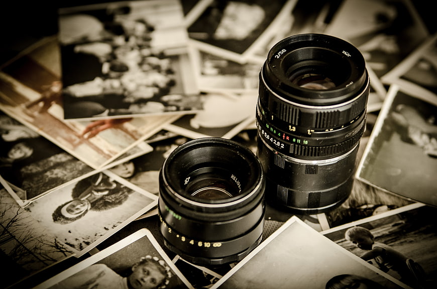 Vintage camera lenses on scattered black and white photographs