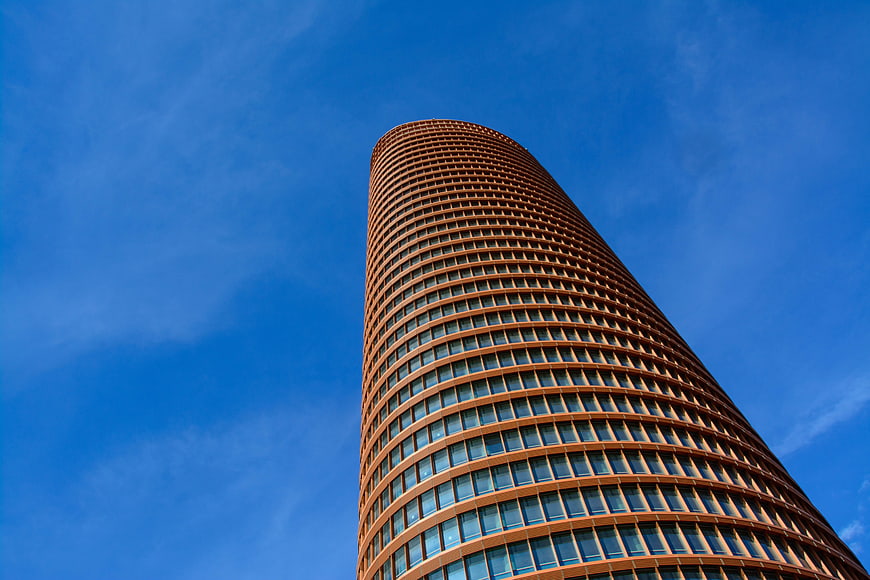 Low angle view of modern cylindrical skyscraper against blue sky