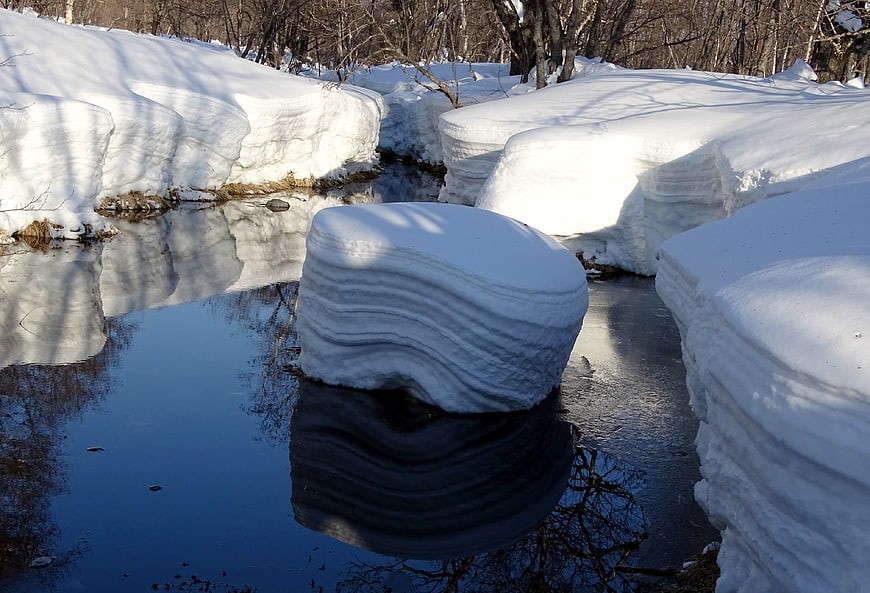 Layered snow drifts in a winter forest stream