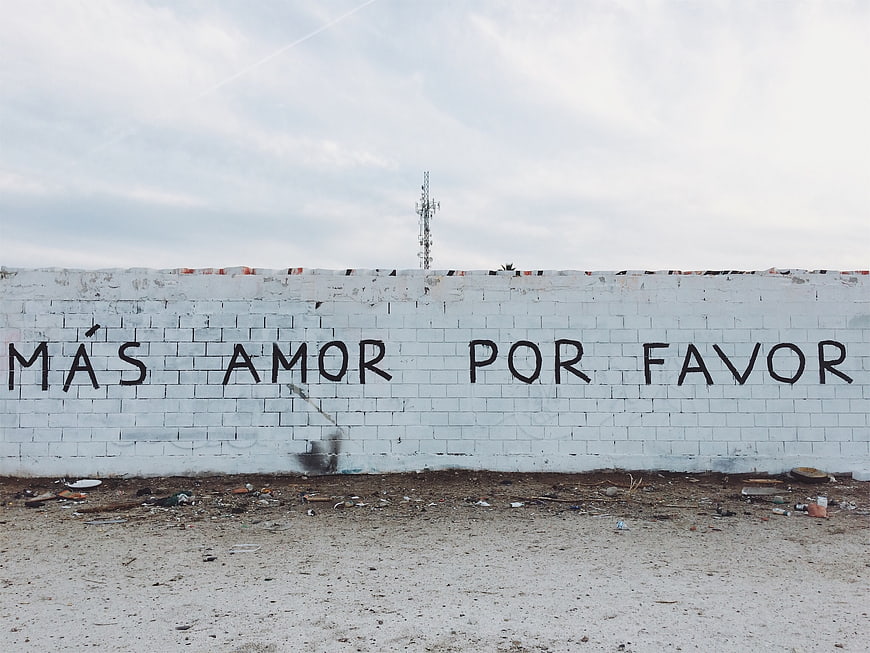 Spanish graffiti wall reading Más amor por favor