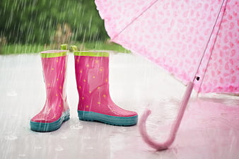 Pink rain boots and umbrella in the rain