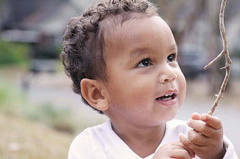 Close-up of happy toddler boy holding stick outdoors