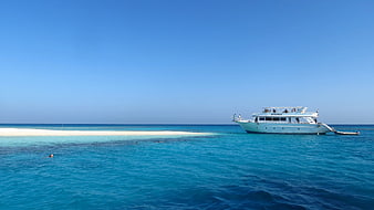 White yacht anchored near sandbar in turquoise ocean