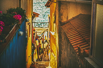 Narrow Greek alleyway with taverna sign and sea view