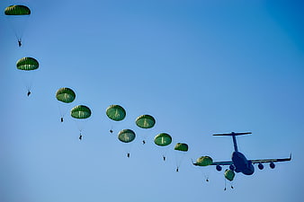 Military Paratroopers Jumping from Transport Aircraft in Blue Sky