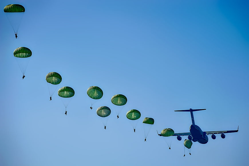 Military Paratroopers Jumping from Transport Aircraft in Blue Sky