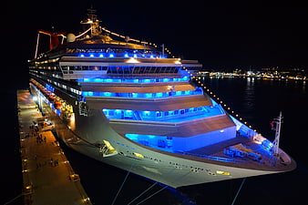 Carnival Destiny cruise ship docked at port at night with blue lighting
