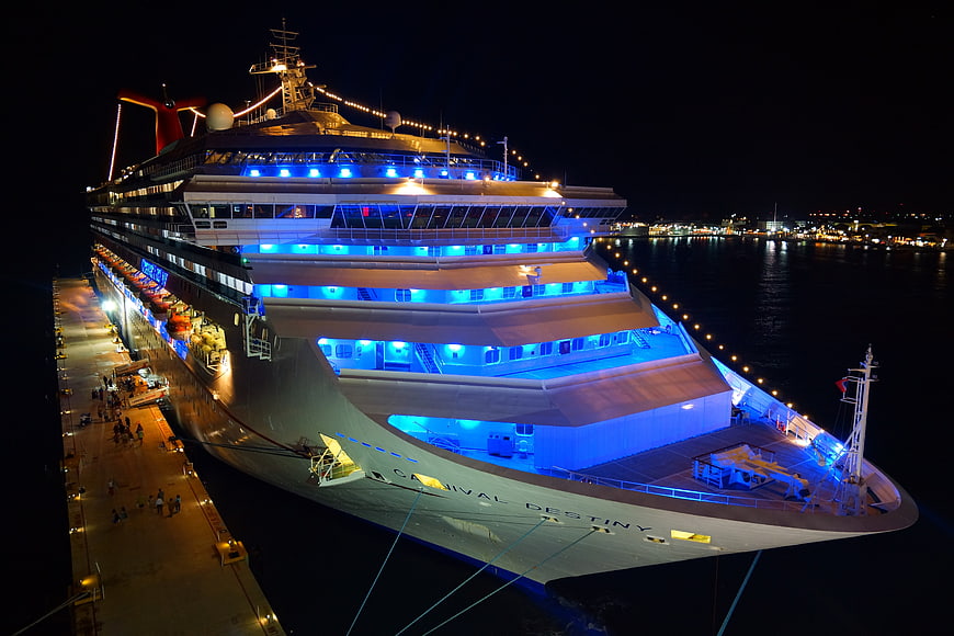 Carnival Destiny cruise ship docked at port at night with blue lighting