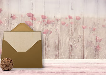 Gold envelope with twine ball on rustic wooden background with floral overlay