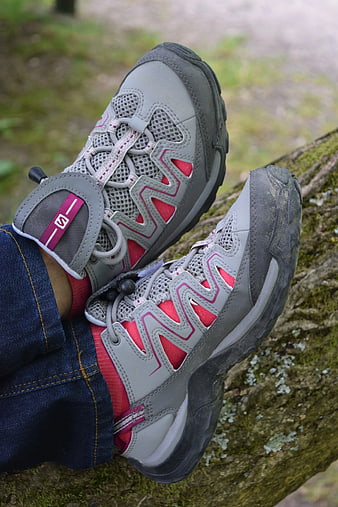 Child's feet in gray and pink Skechers hiking shoes on a log