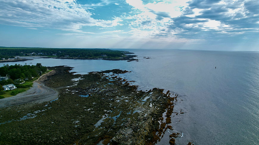 Aerial View of Rocky Coastline with Blue Ocean and Cloudy Sky