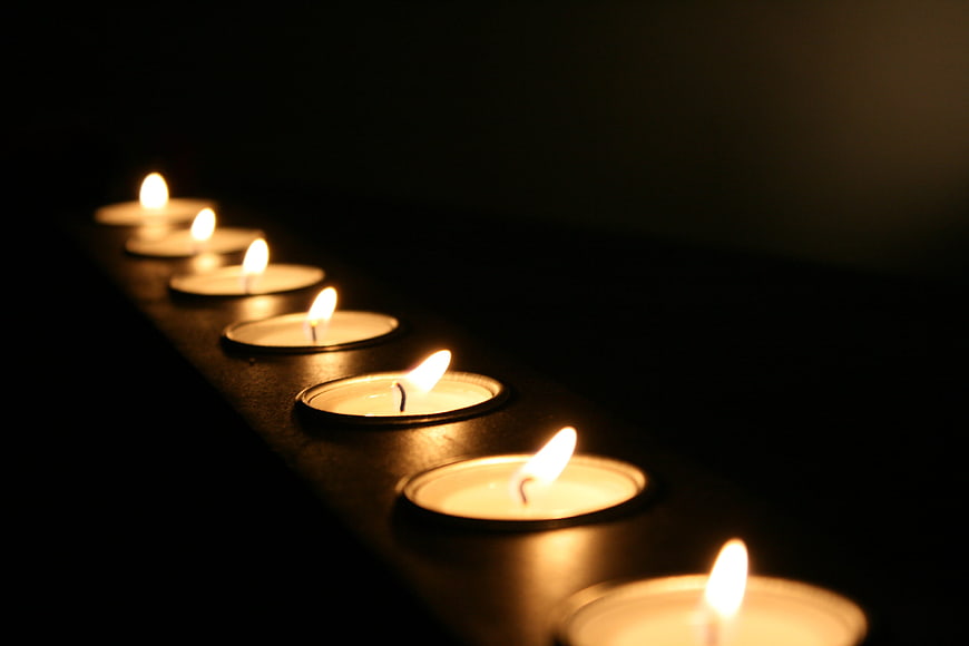 Row of lit tea light candles in dark atmosphere