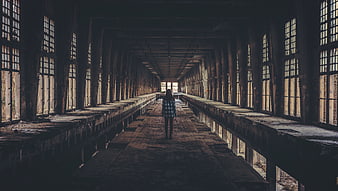 Woman walking alone in abandoned industrial warehouse