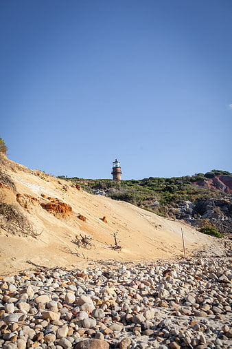 Lighthouse on Sandy Cliff Overlooking Rocky Beach