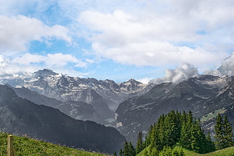Majestic Alpine Mountain Range Panorama With Snowy Peaks And Green Forestry