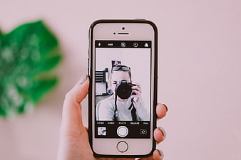 Hand holding smartphone taking mirror selfie photo