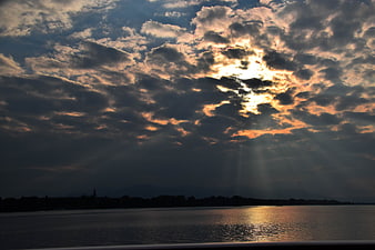Dramatic sunset over lake with sunbeams through clouds