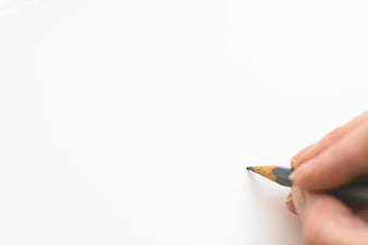 Hand holding pencil on white paper with copyspace