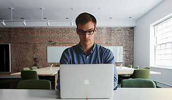 Young man working on a laptop in a modern brick office