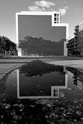 Black and white modern building reflected in urban puddle