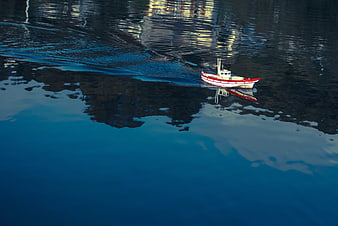Aerial view of red and white model boat on blue water