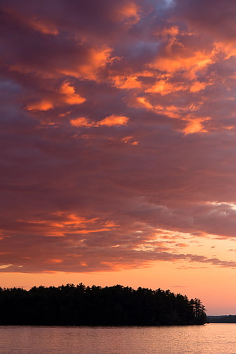 Dramatic Orange Sunset Sky Over Silhouetted Forest and Lake