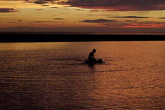 Silhouette of Person on Boat at Golden Sunset