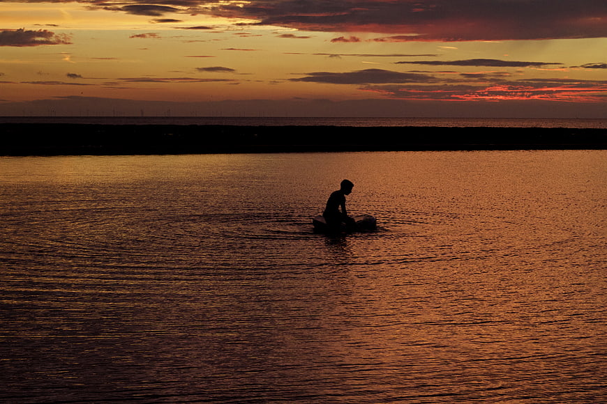 Silhouette of Person on Boat at Golden Sunset