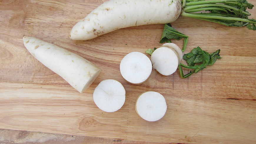 Fresh White Radish And Sliced Rounds On Wooden Cutting Board