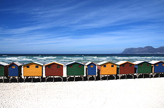 Colorful Beach Huts on Sandy Shore with Ocean and Mountains