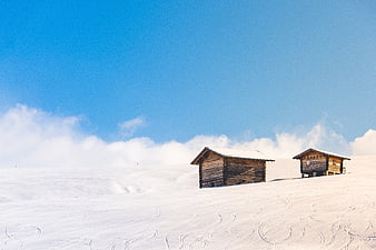 Rustic wooden cabins in snowy mountain landscape with blue sky