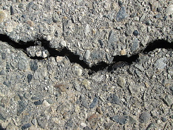 Close-up of cracked asphalt road surface with gravel texture