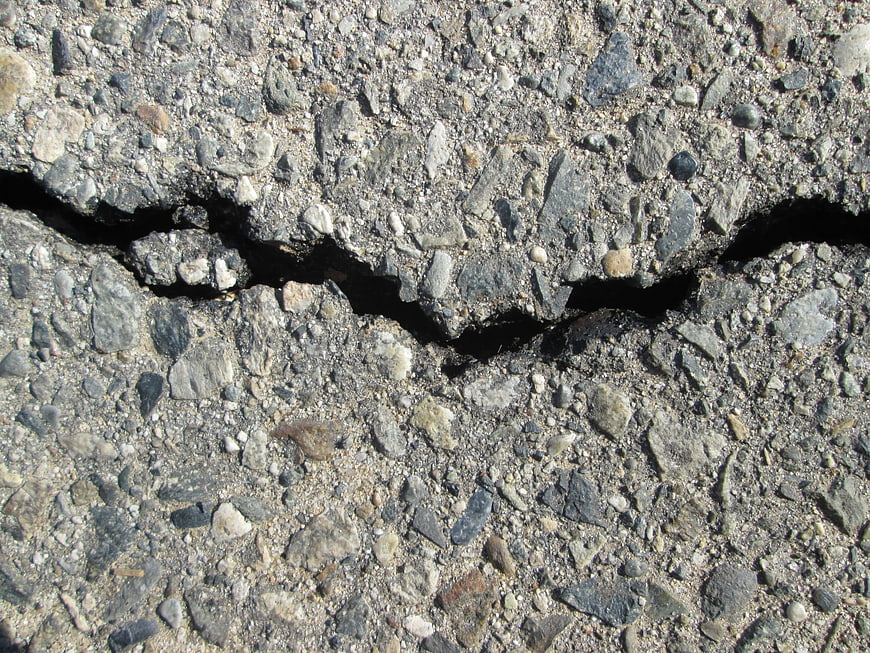 Close-up of cracked asphalt road surface with gravel texture