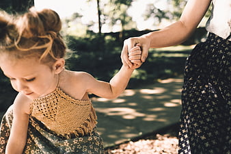 Mother and Daughter Holding Hands in Sunlit Park