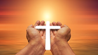 Hands holding glowing white cross against warm sunset background