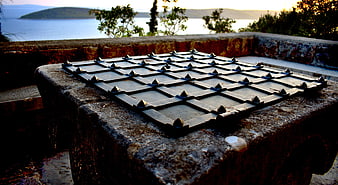 Rusty Metal Grid Cover On Stone Well With Coastal View
