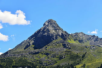 Majestic Rocky Mountain Peak with Green Slopes Under Blue Sky