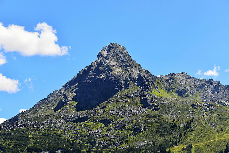 Majestic Rocky Mountain Peak with Green Slopes Under Blue Sky