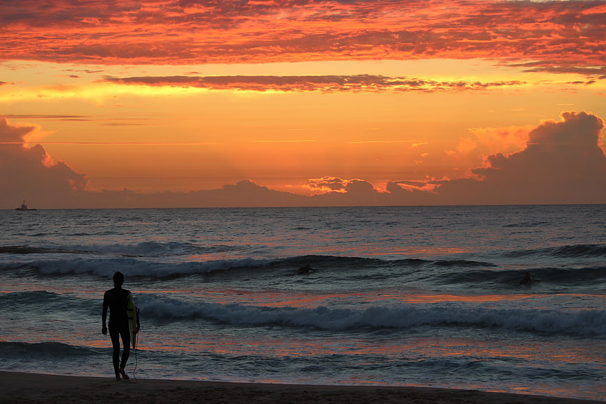 Surfer Silhouette Walking on Beach at Vibrant Sunset